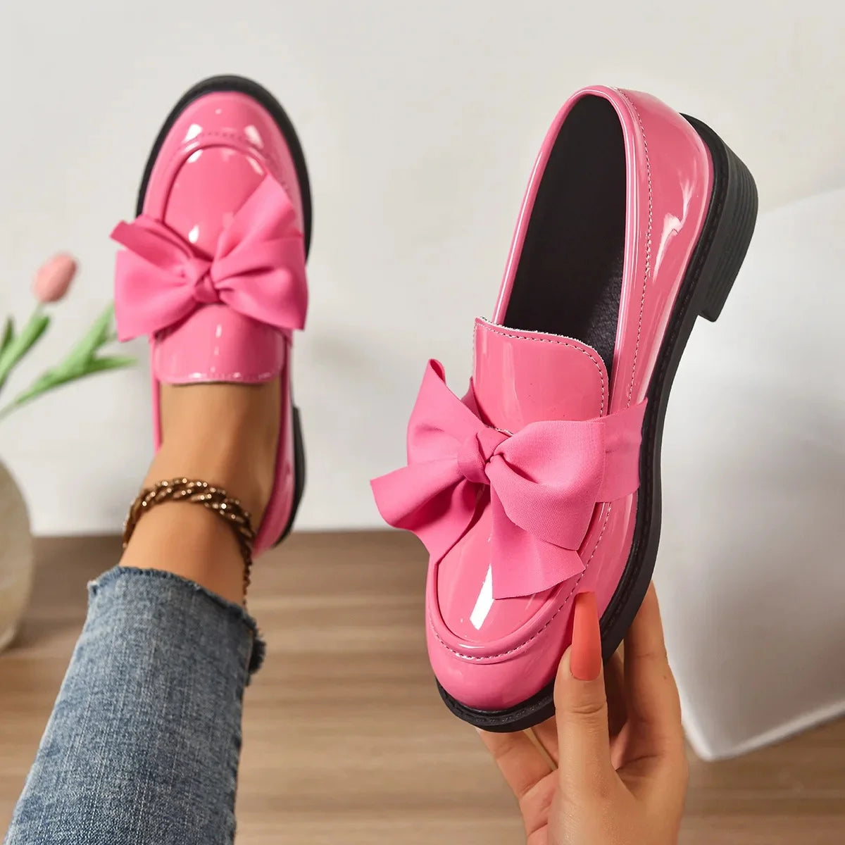 Pink loafers with large bows worn by a person indoors.