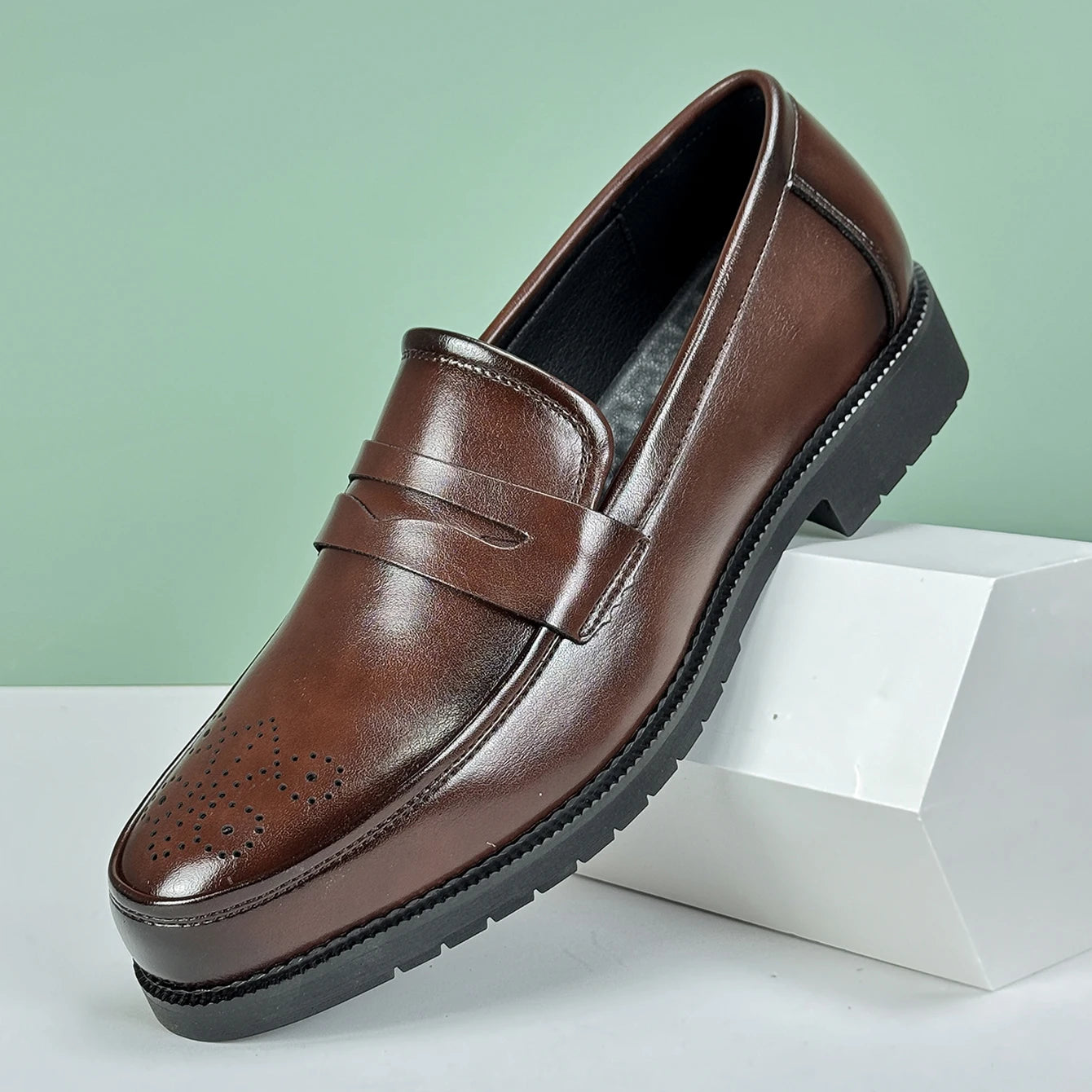 Brown leather loafer shoe on a light green background