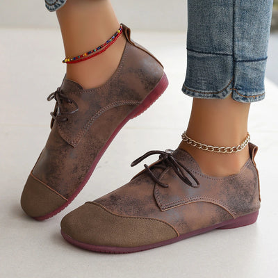 Brown leather shoes worn with rolled-up jeans on a light background