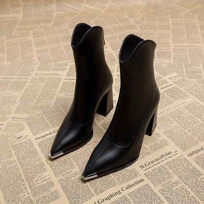Black high-heeled ankle boots on a textured newspaper background