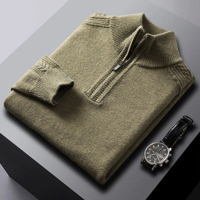 Folded olive green sweater with a watch on a gray surface
