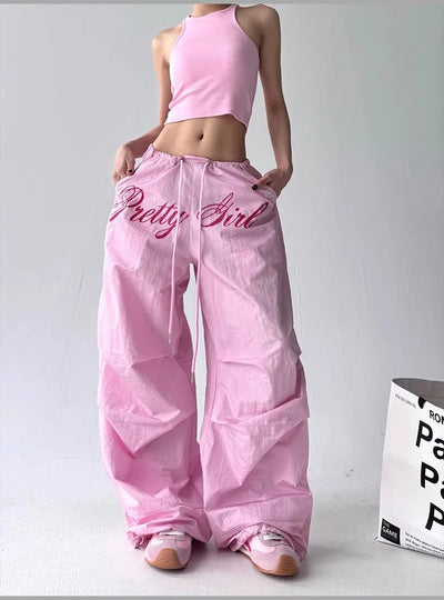 Person wearing pink 'Pretty Girl' pants and matching top on a white background