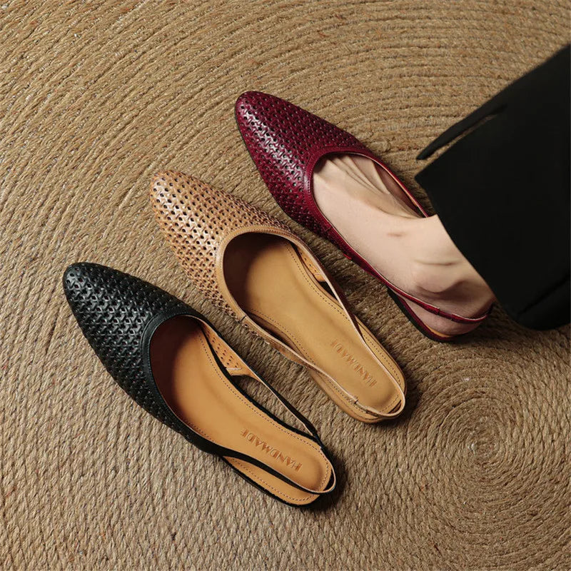 Three flat shoes in black, brown, and red on a textured surface
