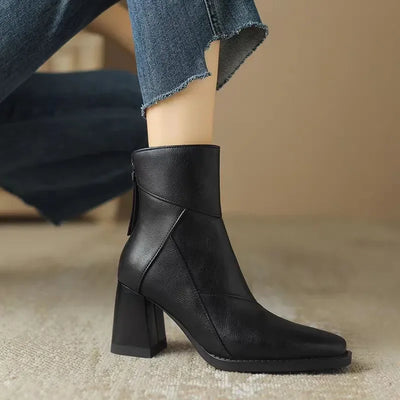 Black ankle boot worn with jeans on a neutral background