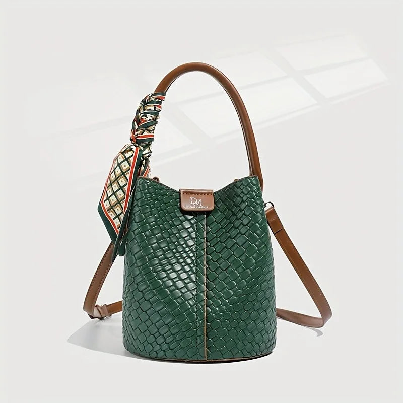 Green textured handbag with brown handle and strap on a white background