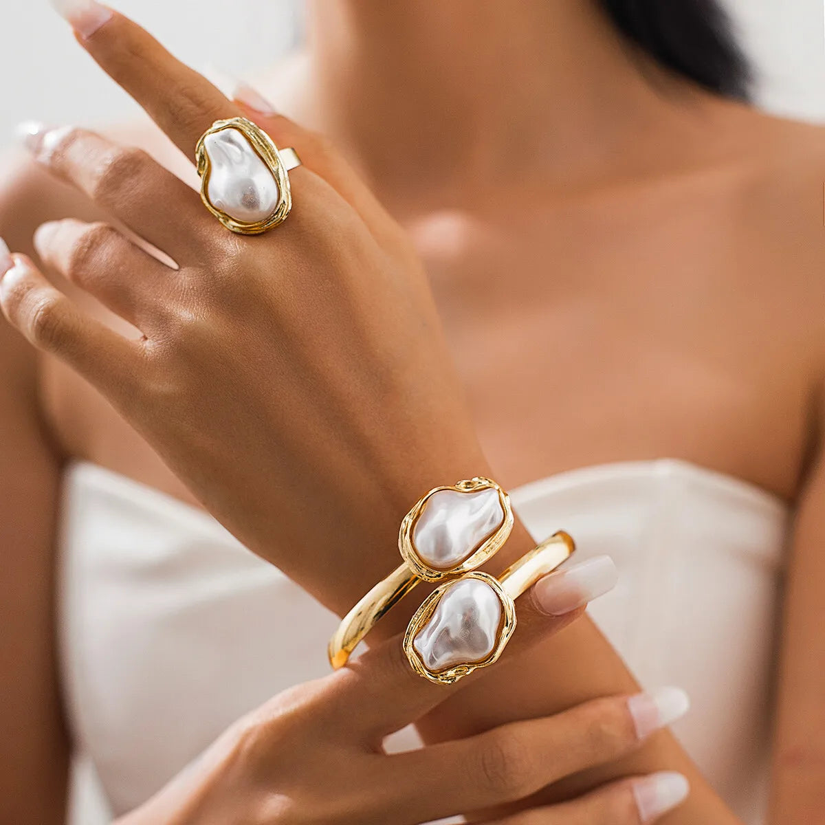 Gold rings with pearl-like stones on a hand against a blurred background