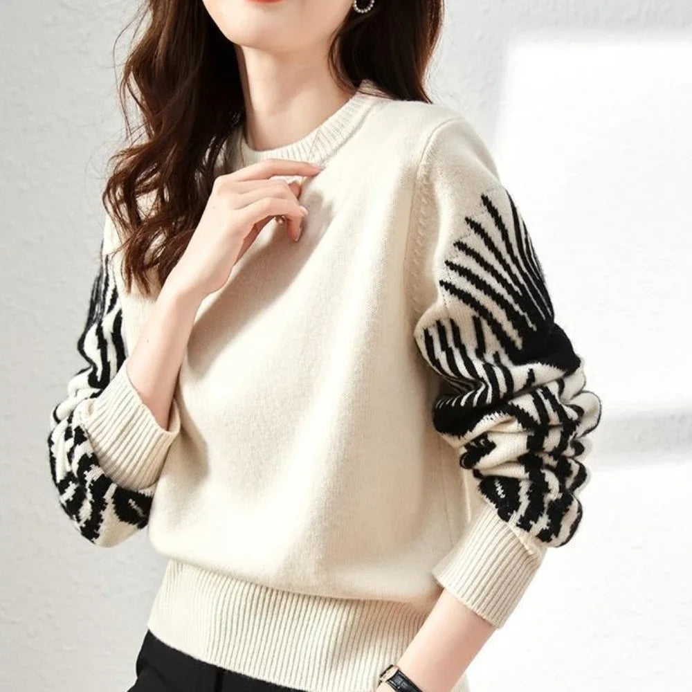 White sweater with black and white patterned sleeves on a plain background