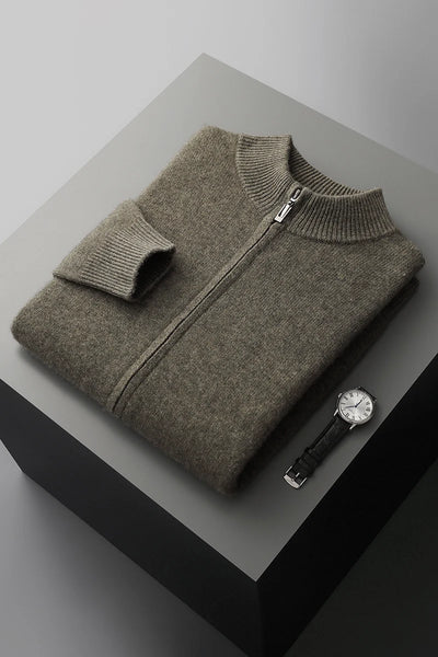 Folded gray sweater with a watch on a gray surface