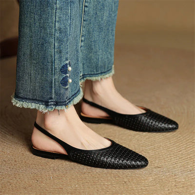 Black woven flats worn with blue jeans on a brown surface