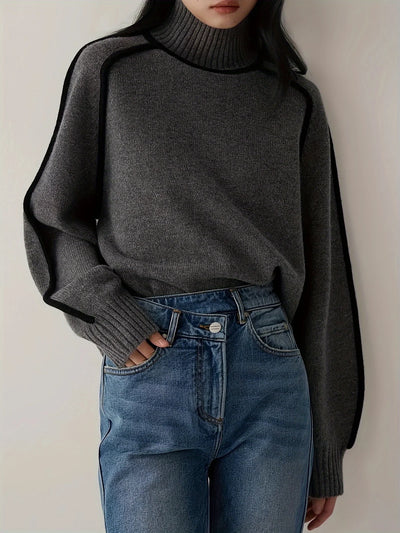 Person wearing a dark gray sweater and blue jeans against a plain background