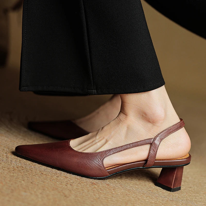 Brown leather slingback shoes worn with black pants on a neutral background