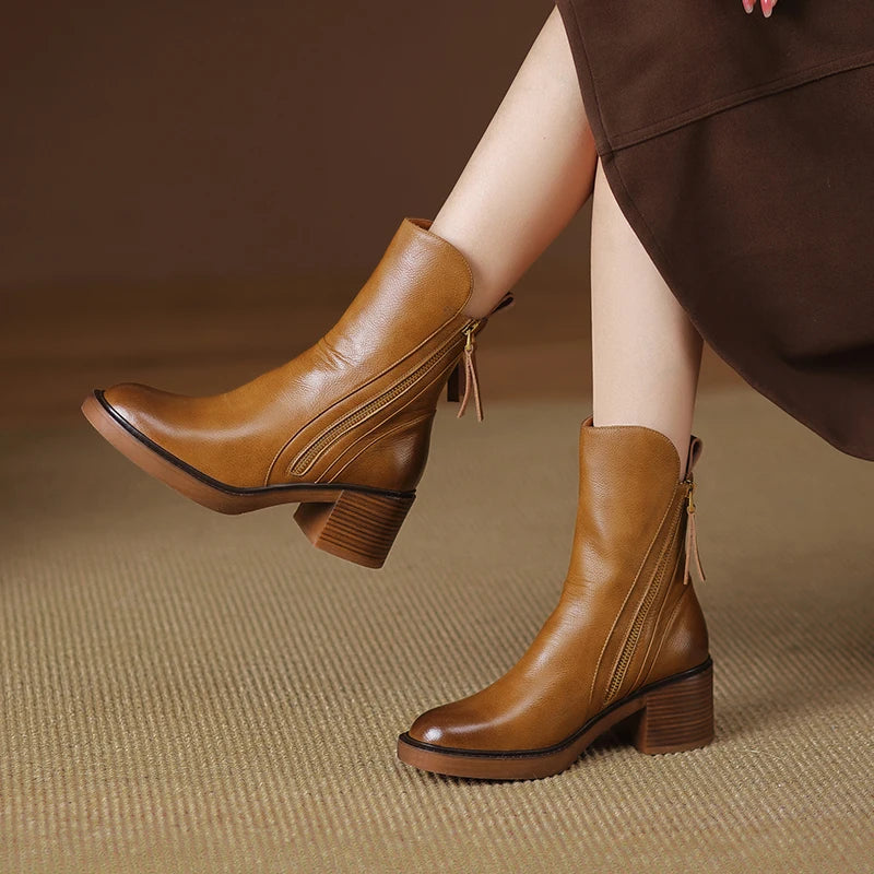 Brown leather ankle boots worn by a person on a brown textured background
